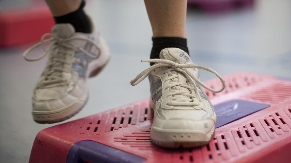 Nahaufnahme eines Sportschuhs auf einem pinken Stepper im Fitnessstudio.